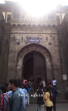 people are standing in front of the entrance to an old building with sun shining on it