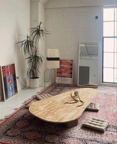 a large wooden table sitting on top of a rug in a living room next to a potted plant