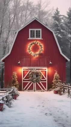 a red barn with a wreath on the door and lights hanging from it's windows