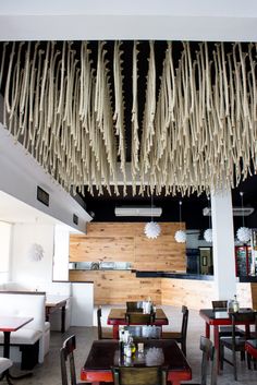 the interior of a restaurant with many wooden sticks hanging from the ceiling and chairs around the tables