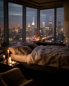 a bedroom with a large window overlooking the city lights and candles are lit up on the bed