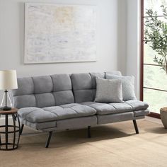 a living room with a gray couch and two lamps on the table next to it