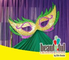 a mardi gras mask on top of a green tent with purple drapes