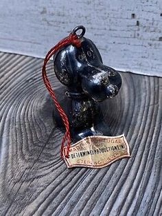 an old fashioned black bear ornament with a red string hanging from it's neck