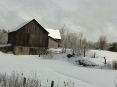 an old barn in the middle of winter with snow on the ground and trees around it