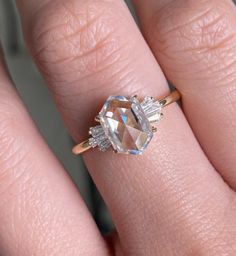 a woman's hand with an engagement ring on top of her finger, showing the center stone