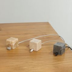 three cubes connected to wires on top of a wooden table