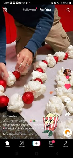 someone decorating cupcakes with white frosting and red decorations