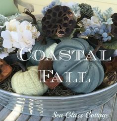 a metal container filled with lots of different types of pumpkins and flowers on top of a wooden table