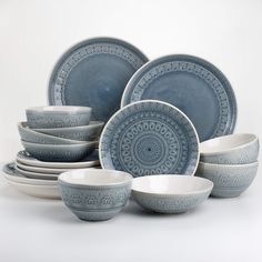 a blue and white dinnerware set on a white background with an intricate design in the center