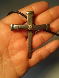 a person holding a small metal cross in their hand