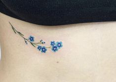 a woman's stomach with small blue flowers on the side and behind her belly