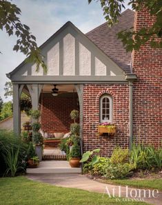 a brick house with potted plants on the front porch and an awning over it