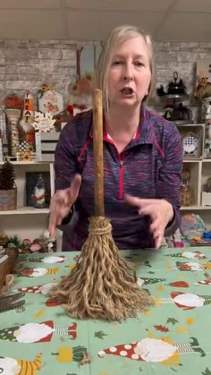 a woman standing in front of a table with a broom on it