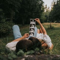 two people laying in the grass with their feet up and one person reading a book