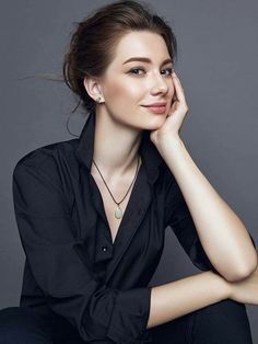 a woman sitting down with her hand on her chin and looking off to the side