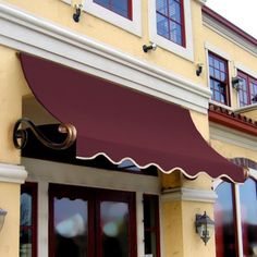 an awning on the side of a building with red shutters and white trim