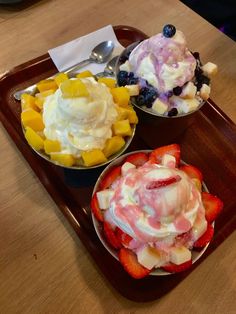 three bowls of ice cream and fruit on a tray