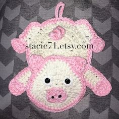 a pink and white crocheted pig ornament hanging on a black background