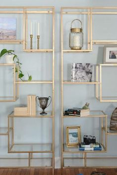 the shelves are filled with books, pictures and vases in gold frames on blue walls