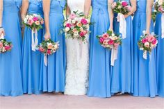 a group of bridesmaids in blue dresses holding bouquets with pink and white flowers