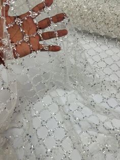 a person's hand on top of a white dress with silver sequins