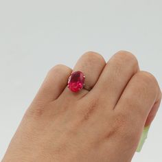 a woman's hand holding a ring with a large red stone in the middle