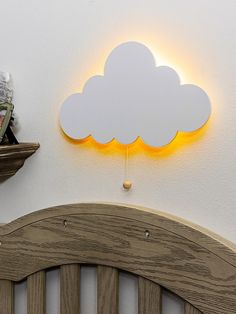 a wooden headboard with a cloud shaped light above it on the wall next to a shelf