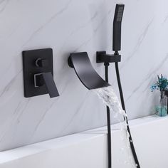 a black faucet with water running from it in a white bathtub next to a marble wall