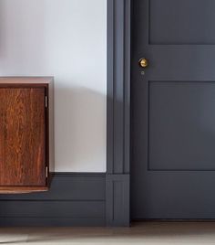 an empty room with a wooden cabinet next to the door