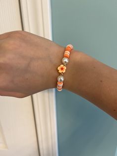 A clay bead bracelet with orange, dark orange, light orange, and white clay beads with round pearls, round gold beads, and an orange flower charm. Orange Beaded Bracelets, Orange Hibiscus, Bff Bracelets, Clay Bead Bracelet, Bracelets Handmade Diy, Orange Stone, Bead Charms Diy, Diy Bracelet Designs, Bead Ideas