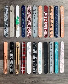 several skateboards are lined up on a wooden surface, with different designs and words painted on them