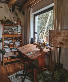 a room with a wooden desk and lots of books on shelves next to a window