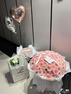 two large bouquets of roses are on display in front of the wall with balloons