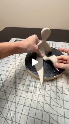 two hands are working on an object that appears to be spinning in the air, while another hand is holding it