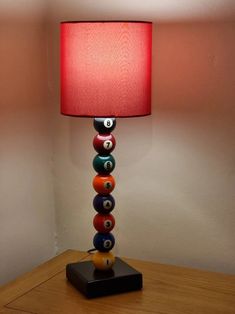 a lamp that is sitting on top of a wooden table in front of a wall