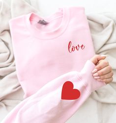 "Express your love with style and warmth with our \"Love Heart Sweatshirt.\" This charming and trendy sweatshirt is more than just a piece of clothing; it's a heartfelt declaration of love and a fashionable addition to your wardrobe. The iconic heart design adds a touch of romance, making it a perfect choice for a Valentine's Day gift or any day you want to wear your heart on your sleeve. Whether you're looking for a thoughtful gesture for a loved one or a stylish way to express your affection, the \"Love Heart Sweatshirt\" is designed to make a statement. Embrace the joy of love with this trendy and heartwarming sweatshirt that seamlessly combines comfort and style. Variety of Colors: Sweatshirt: Sand, Maroon, Light Pink, Sport Grey, Navy T-Shirt: Heather Dust, Heather Maroon, Pink, Athle Valentines Graphic Tee, Valentines Sweater, Valentines Day Sweatshirt, Valentines For Mom, Red Sweatshirt, Cute Shirt Designs, Valentine Print, Heart Sweatshirt, Pink Valentines