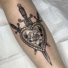 a black and white photo of a heart with two swords on it, surrounded by flowers