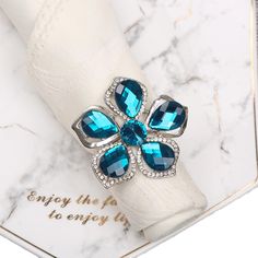 a napkin ring with blue stones on it and a white napkin in front of the napkin