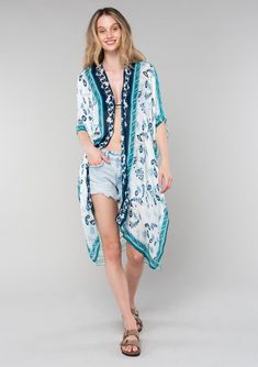 [Color: Ivory/Teal] A front facing image of a blonde model wearing a mid length bohemian kimono in an ivory and teal paisley and floral print. With half length kimono sleeves Casual Patterned Kimono For Beach Cover-up, Bohemian Relaxed Fit Kimono For Daywear, Casual Spring Paisley Print Kimono, Casual Summer Kimono With Paisley Print, Casual Summer Paisley Print Kimono, Spring Paisley Print Open Front Kimono, Spring Open Front Paisley Print Kimono, Casual Patterned Kimono With Boho Print, Casual White Floral Print Kimono