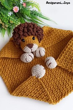 a crocheted lion on top of a yellow blanket next to a potted plant