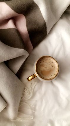 a cup of coffee sitting on top of a white blanket