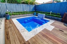 a small pool in the middle of a wooden decked area with blue walls and plants