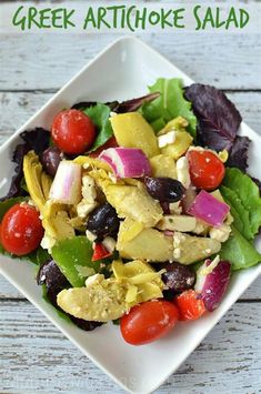 greek artichoke salad with olives, tomatoes and lettuce on a white plate