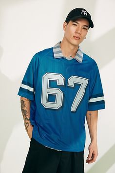 Football jersey from Standard Cloth. Short sleeve mesh jersey features varsity-inspired graphics at the front and back, complete with contrast striping and raglan seams. Features Football jersey from Standard Cloth Mesh fabrication Front and back graphics Raglan construction Contrast striping at sleeves Short sleeves Content + Care Machine wash Imported Size + Fit Model is 5’11.5" and wearing size Medium Measurements taken from size Medium Chest: 24.5" Length: 28" | Standard Cloth Football Jersey Top in Blue, Men's at Urban Outfitters Blue Baseball Collar Top For Fan Gear, Blue Top With Baseball Collar For Fan Gear, Blue Fan Gear Top With Baseball Collar, Blue Baseball Collar Top For Game Day, Varsity Jersey With Team Logo For Sports Season, Varsity Jersey With Team Logo, Sporty Blue Baseball Jersey For Fan Gear, Blue Sporty Baseball Jersey For Game Day, Sporty Blue Baseball Jersey For Game Day