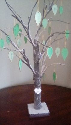 a small tree with hearts hanging from it's branches on top of a table