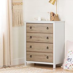 a white dresser sitting next to a window in a room with a rug on the floor