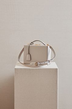 The Grace Box has been a signature Mark Cross style since the 1950’s. The structured square shape was inspired by an overnight case created by the brand for Grace Kelly in the film “Rear Window", and the iconic push-lock closure originates from Mark Cross trunks in the late 1800s. Now reimagined in Light Taupe calfskin leather, the Grace Box offers versatility via both a top handle and shoulder strap. Length: 19.1 cm / 7.5” Height: 14 cm / 5.5” Width: 8.9 cm / 3.5” Strap drop: 50.8 cm / 20" Hand Classic Rectangular Box Bag With Original Box, Designer Formal Box Bag With Rectangular Case, Designer Rectangular Box Bag For Formal Occasions, Designer Formal Rectangular Box Bag, Formal Square Box Bag With Original Box, Classic Box Bag With Palladium Hardware, Timeless Rectangular Box Bag For Formal Occasions, Modern Box Bag With Gold-tone Hardware As Gift, Classic Rectangular Box Bag For Gifts