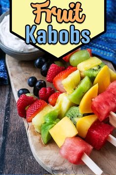 Fruit kebabs on a wooden board with a text overlay title.