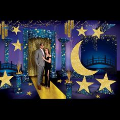 a man and woman standing in front of a photo booth with stars and moon decorations